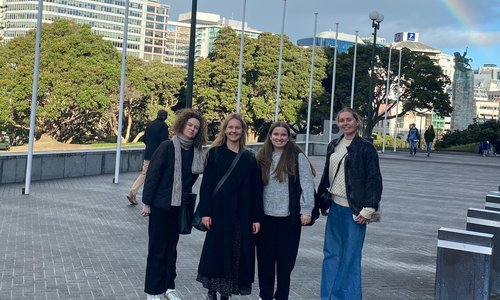 Four women standing under a rainbow