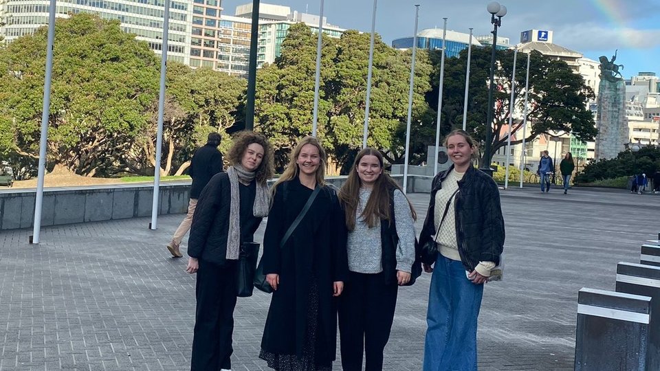 Four women standing under a rainbow