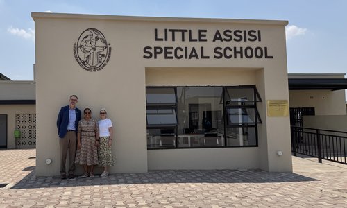 three people standing outside the entrance of a school