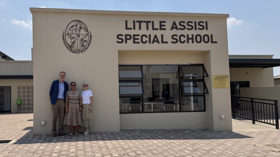 three people standing outside the entrance of a school