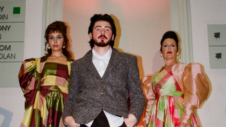 Oran Aurelio with two models wearing his designs on the runway