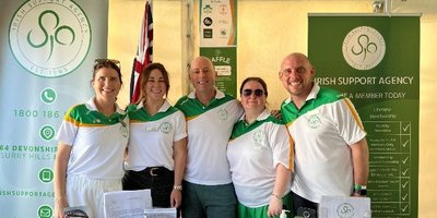 five people in white and green tops in a line smiling at the camera