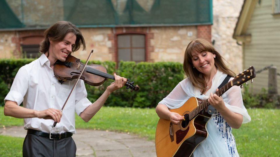 Two people playing the violin and the guitar.