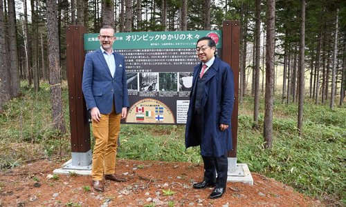 Two men stood in front of a forest in Hokkaido