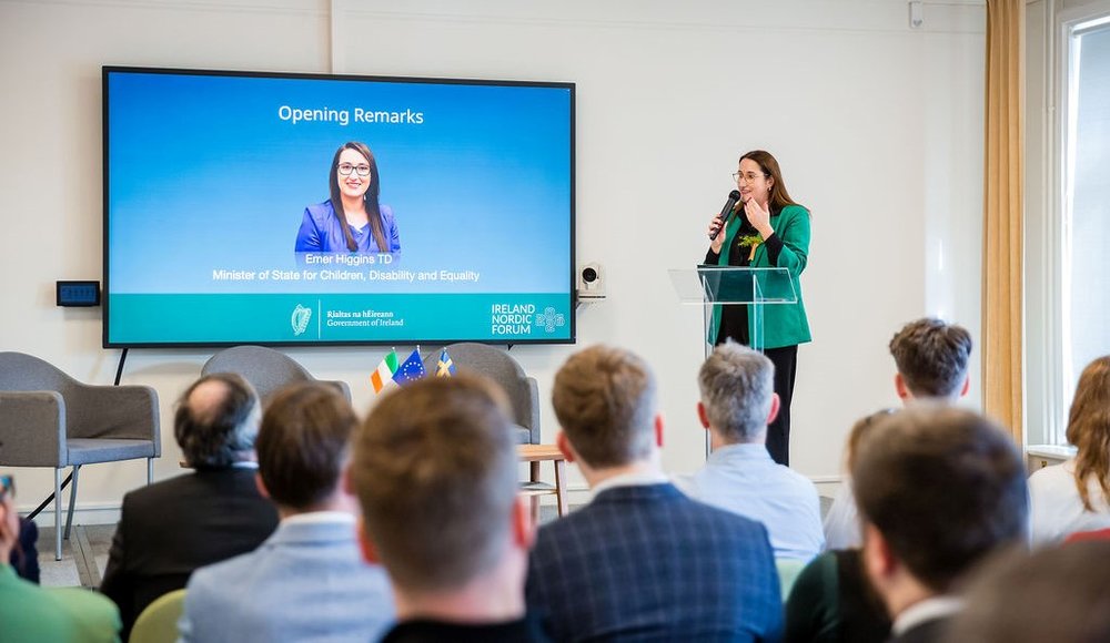 Minister Higgins standing at a podium giving remarks in front of a crowd