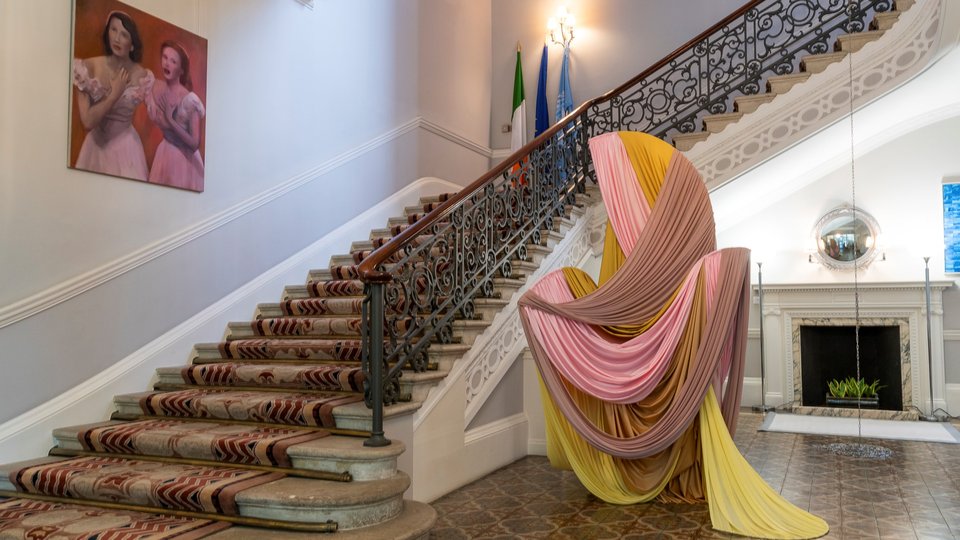 A staircase with art hanging on the wall and a sculpture to the right