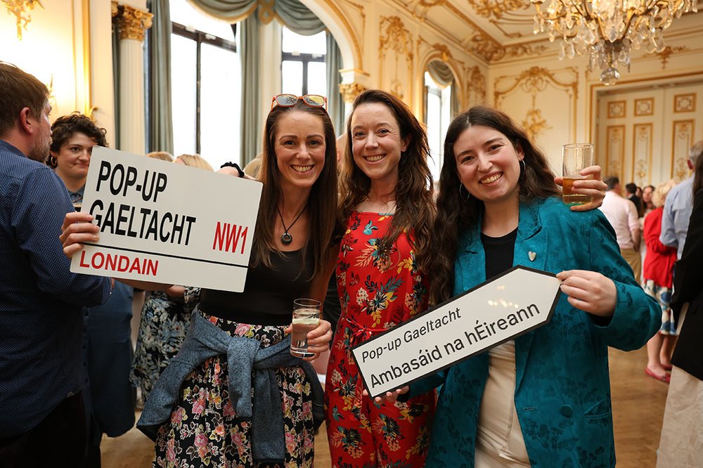 three women holding signs for pop-up Gaeltacht