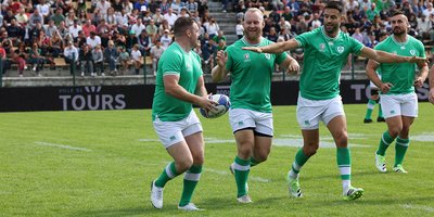 four Irish rugby team members on the pitch with a crowd in the stalls