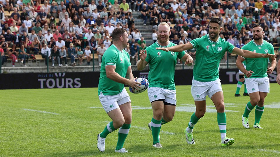 four Irish rugby team members on the pitch with a crowd in the stalls