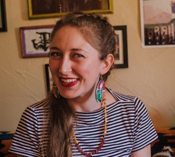 profile shot of woman smiling wearing stripy top and colourful jewellry