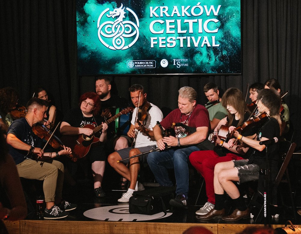 Musicians perform on stage with logo of the festival visible in the background