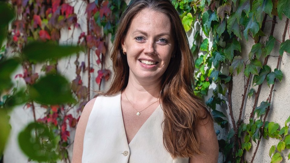 Woman smiling and standing infront of plants