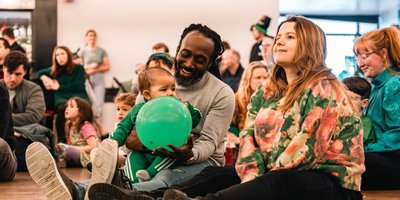 A family sitting on the floor at a community event