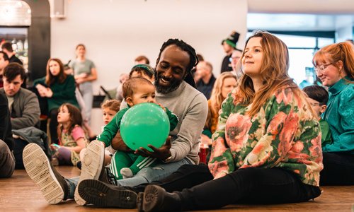 A family sitting on the floor at a community event
