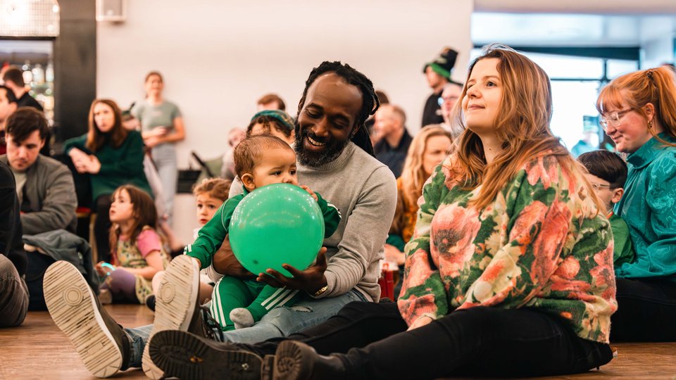 A family sitting on the floor at a community event