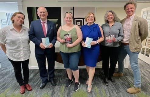 six men and women standing posing for photo in lobby