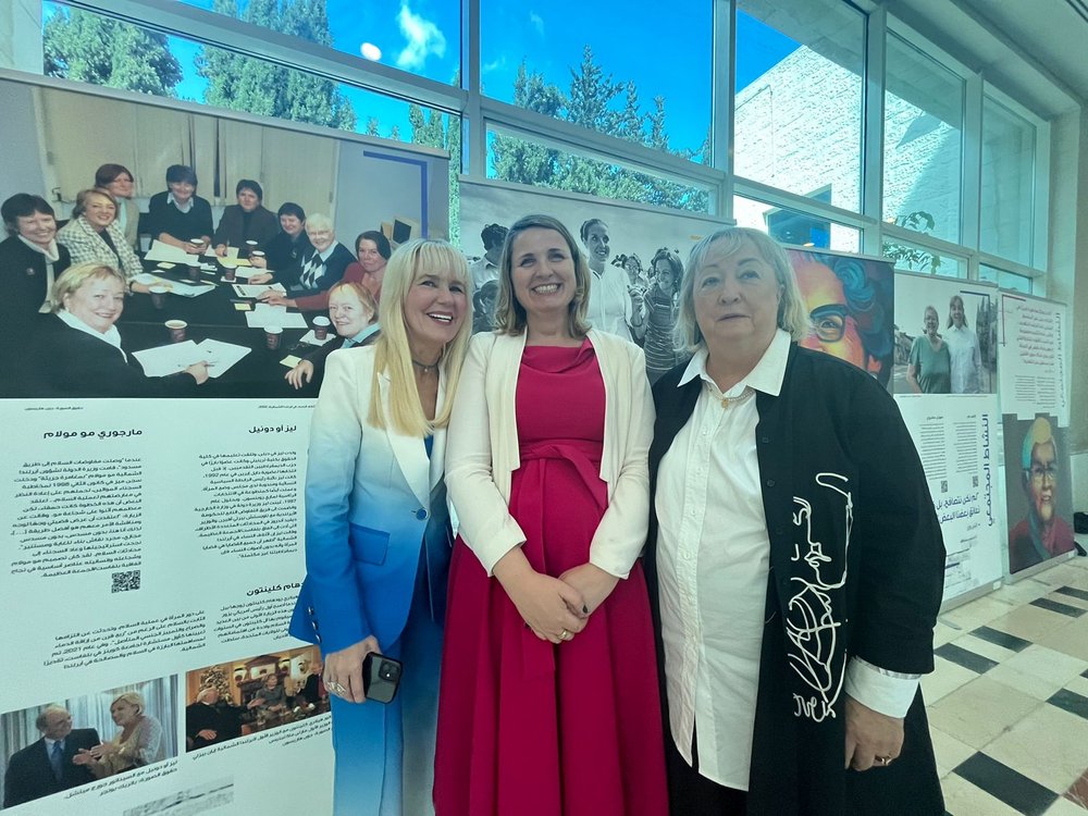 Three women standing in front of the Peace Heroines exhibition