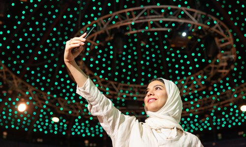 A woman taking a selfie with a background of green lights