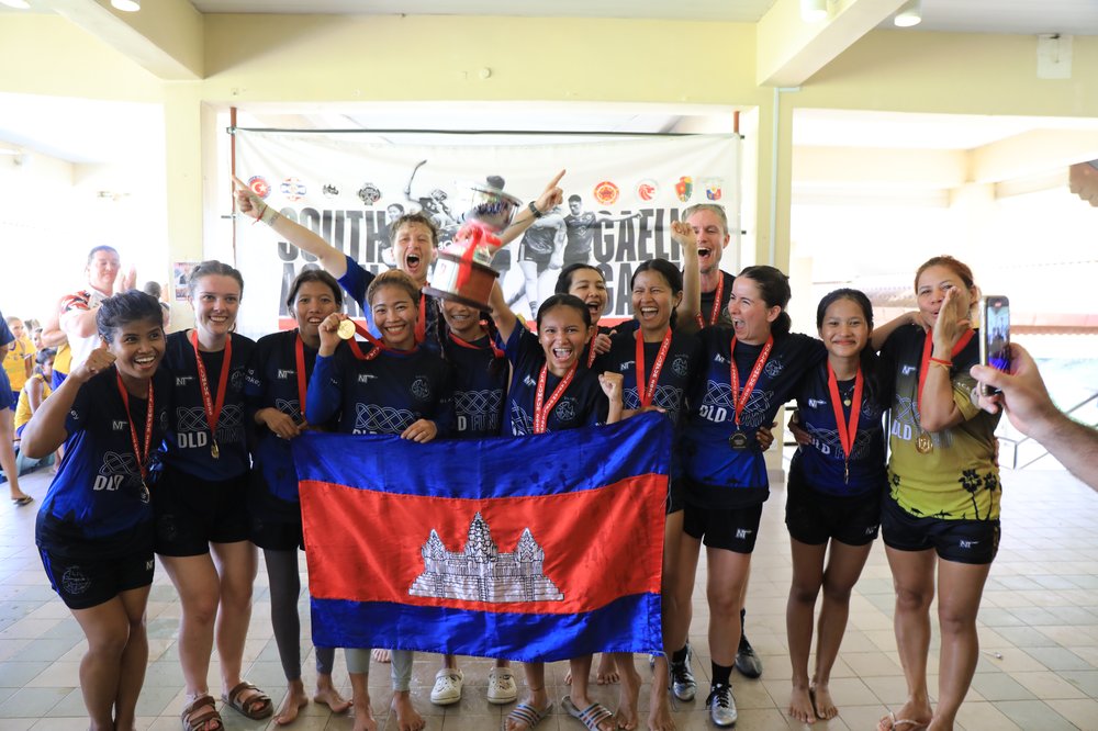 Cairde Khmer women's team celebrating with the Cambodian flag while wearing medals