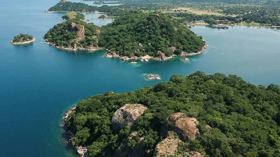 aerial shot with drone of green mountains and blue water in Monkey Bay, Lake Malawi, Malawi
