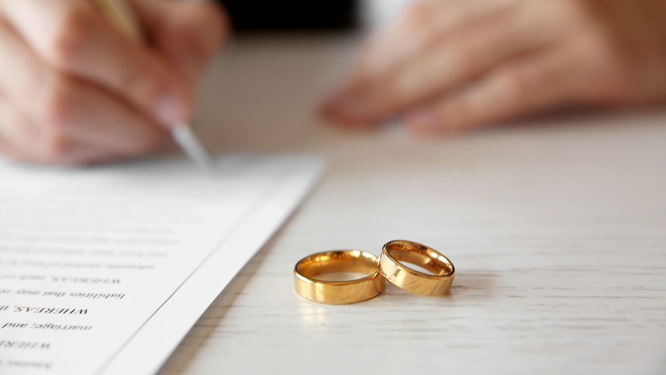 two wedding rings with a person signing a document