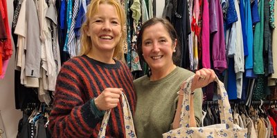 Two women pose with matching tote bags at a Change Clothes Crumlin swap
