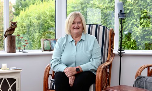 Woman sitting in a chair in a conservatory smiling at the camera
