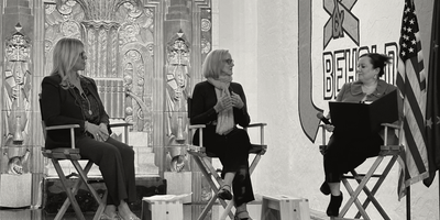 Three women sitting on chairs on a stage talking