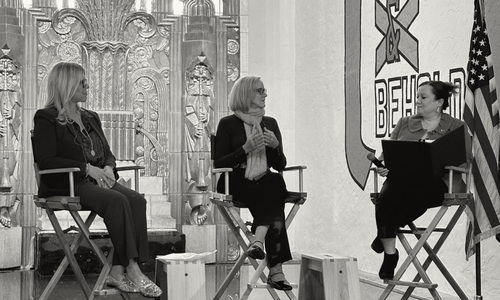 Three women sitting on chairs on a stage talking