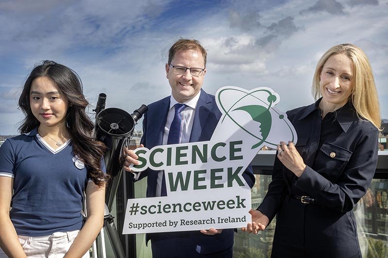 minister lawless with two women holding signs promo for science week