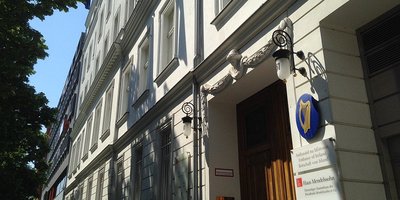 A view of the exterior of the Irish Embassy in Germany building showing the blue escutcheon with a gold harp symbol outside the door.