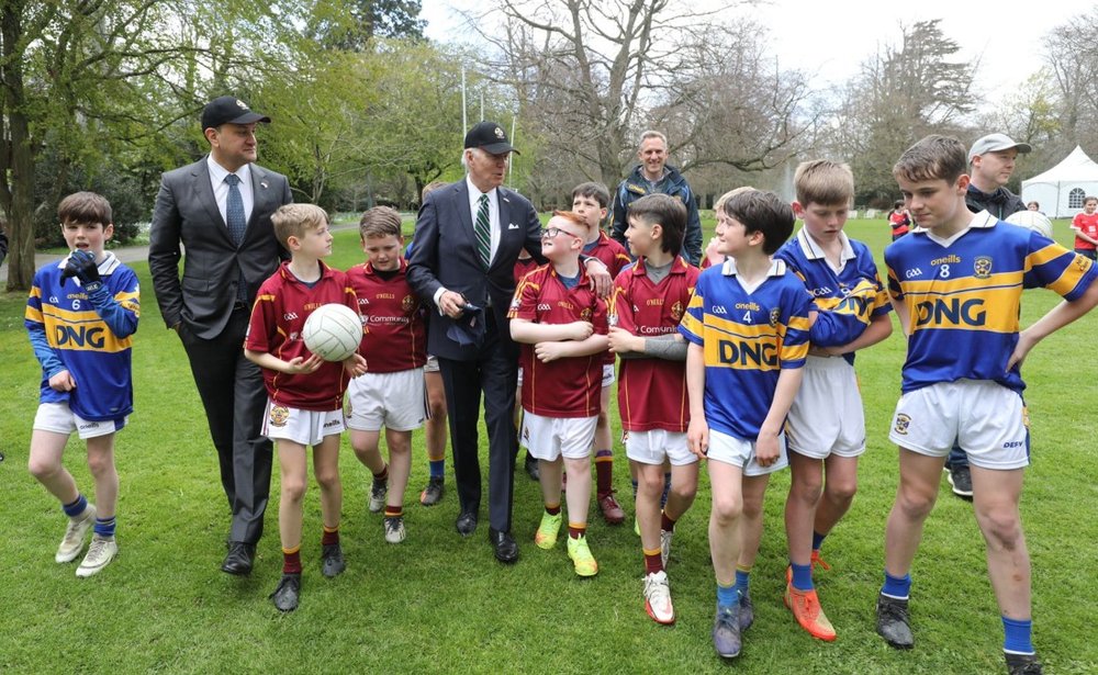 Two men with boys aged 10 - 12 in two different types of GAA uniforms who just played a demonstration game