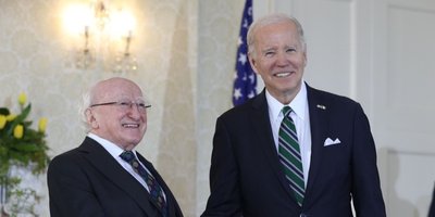 two men shaking hands side on smiling at the camera