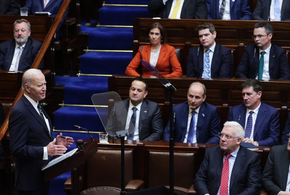 man speaking at a podium with people facing him listening in an auditorium