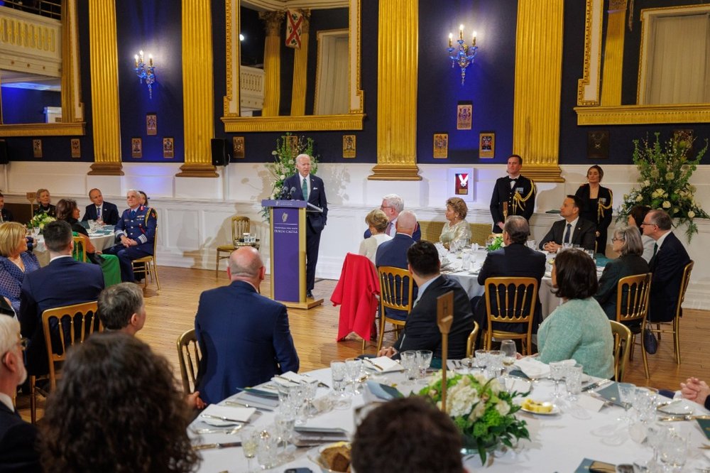 man giving speech with people sitting at round dinner tables listening