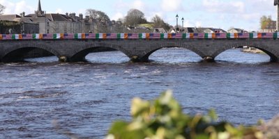 bridge over wide river with Irish and American flags