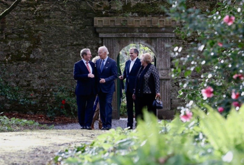 four people standing in rose garden with old stone walls in the background