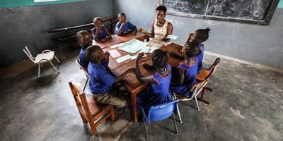 A picture of a classroom with students sitting around one table with a teacher in St Joseph's Compound, a school that educates and teaches hearing impaired children in Makeni Town, Sierra Leone. Africa, 2019