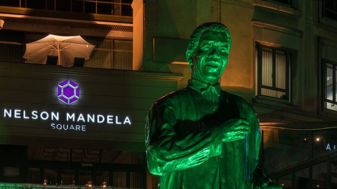 nelson mandela statue at night lit up with green light
