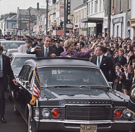 sixties cars with American flags and crowds waving