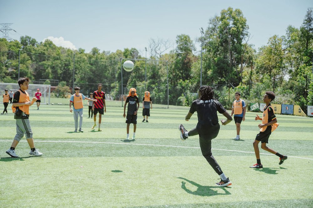 Teenage boys playing GAA on a sunny pitch