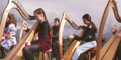 young people playing the harp outdoors