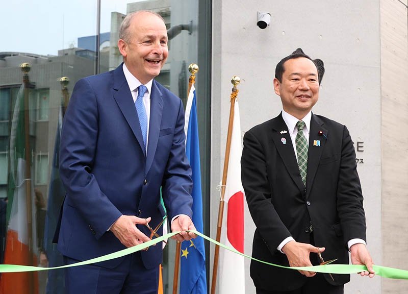 two men one cutting a ribbon for building opening