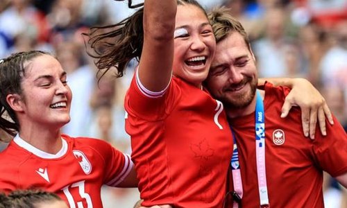 A team celebrating with players jumping in the air and coach hugging one of the players