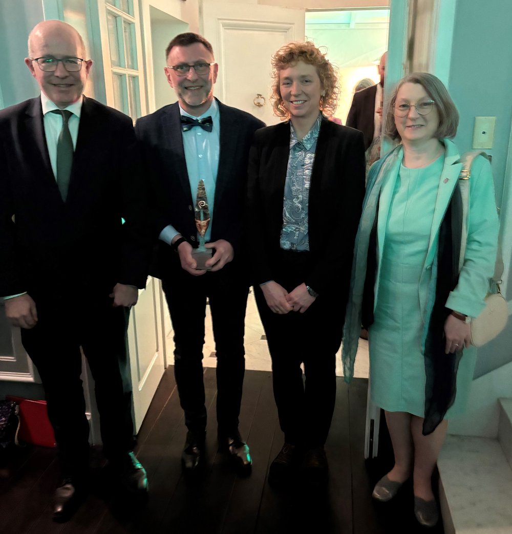 Three members of an association join Ambassador Haughey for a photo