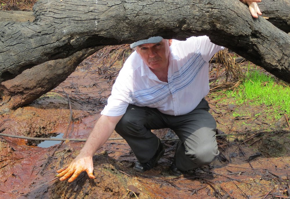 Fr O'Hara touching soil where there has been an oil spill.
