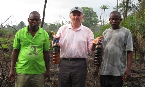 Fr O' Hara standing with two companions showing bottles of collected oil