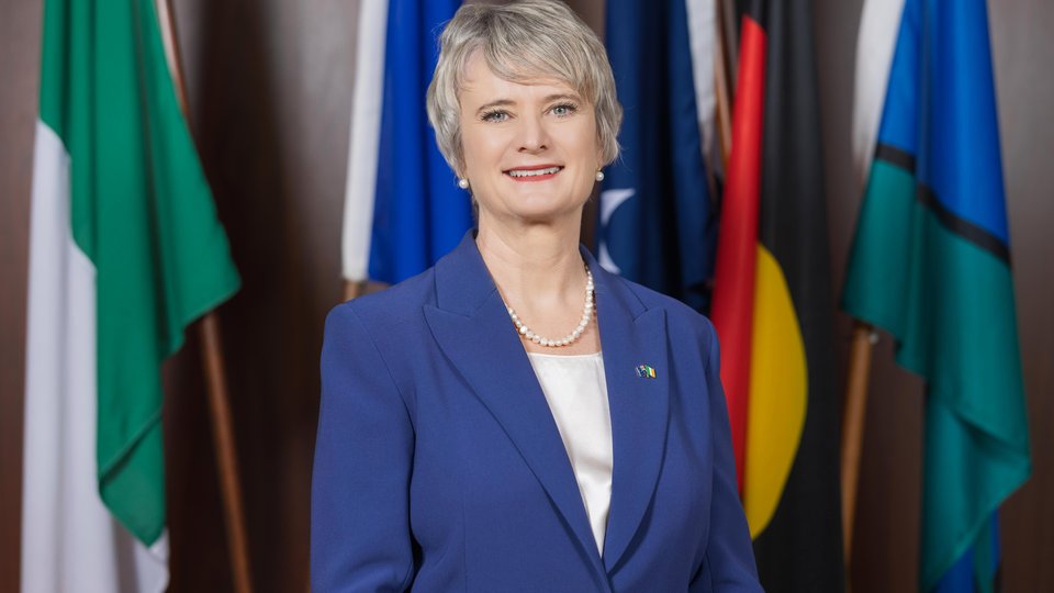 Ambassador in front of the Irish, EU, Australian, Aboriginal and Torres Strait Islander Flags