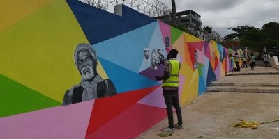 man in high vis vest painting colourful mural on a walkway