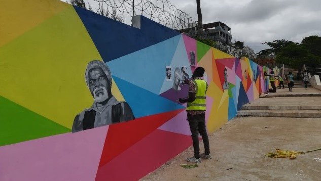 man in high vis vest painting colourful mural on a walkway